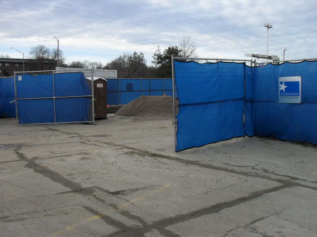 Temporary fencing in Kansas City with blue privacy screens and an open gate.