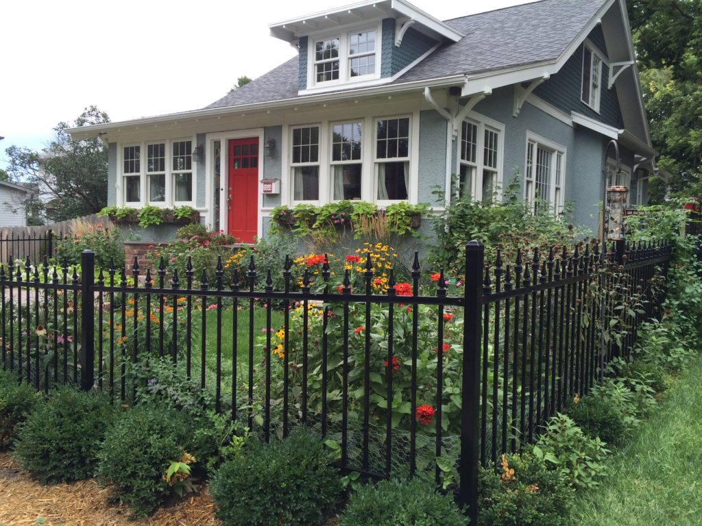 Alternating picket ornamental fence installed in front of a garden in the front yard of a house